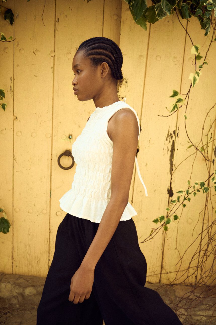 Lightweight white linen smocked sleeveless top with textured finish and gentle volume, paired with relaxed black linen culottes