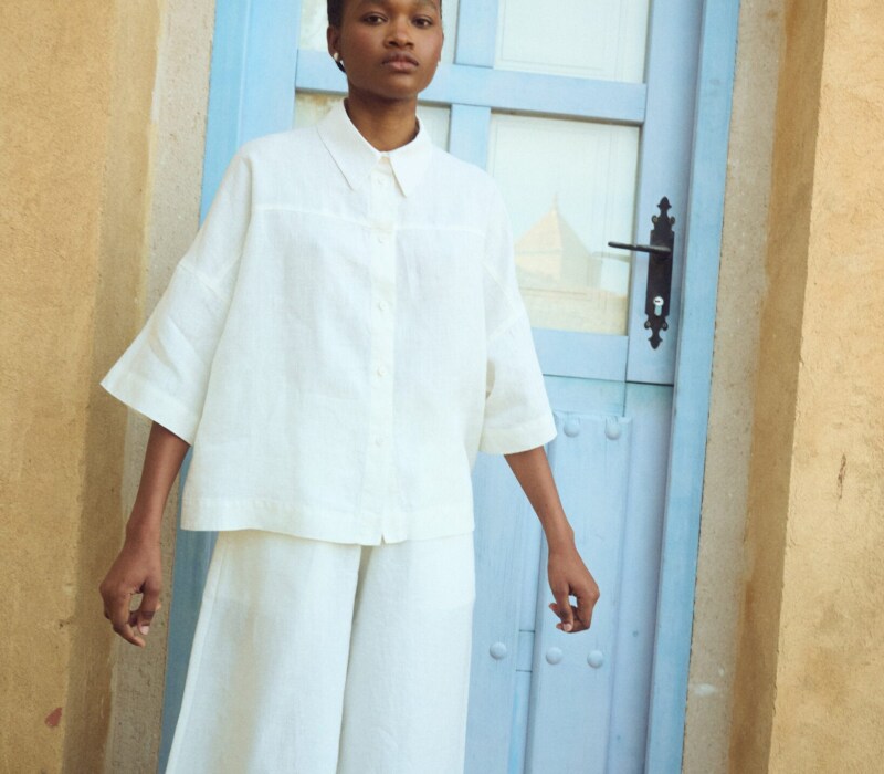 model is wearing oversized white linen shirt and white linen culottes