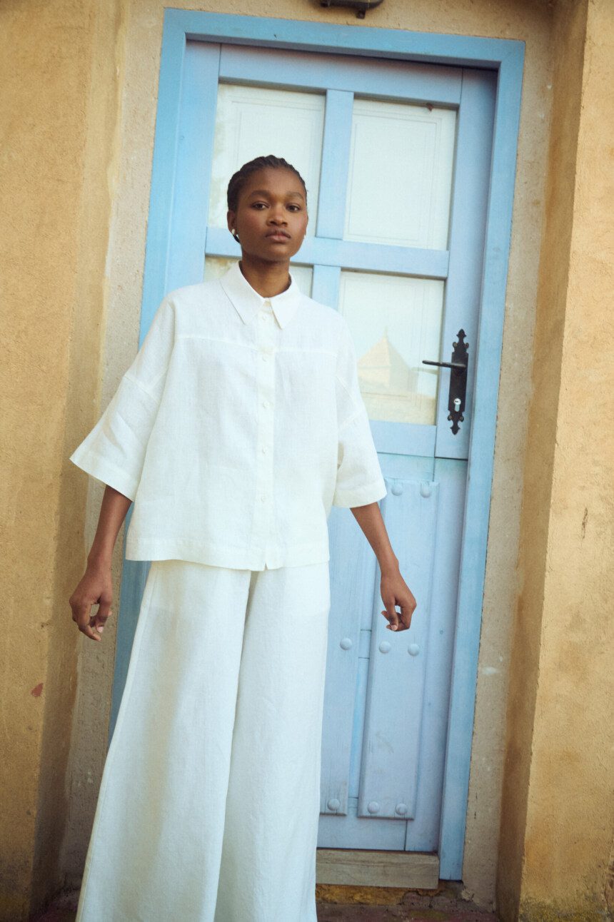 model is wearing oversized white linen shirt and white linen culottes