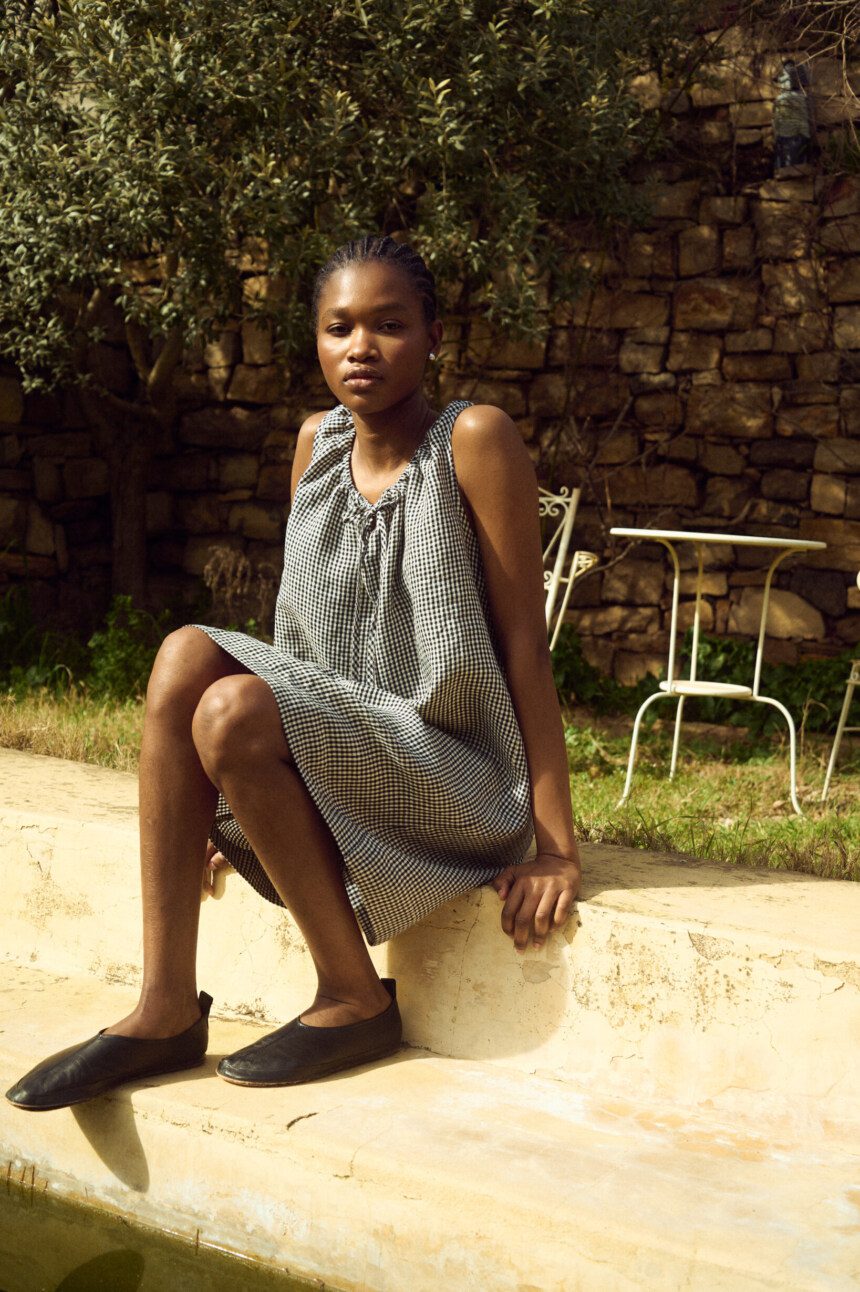 Sleeveless black gingham linen dress featuring a softly gathered neckline with delicate tie detail