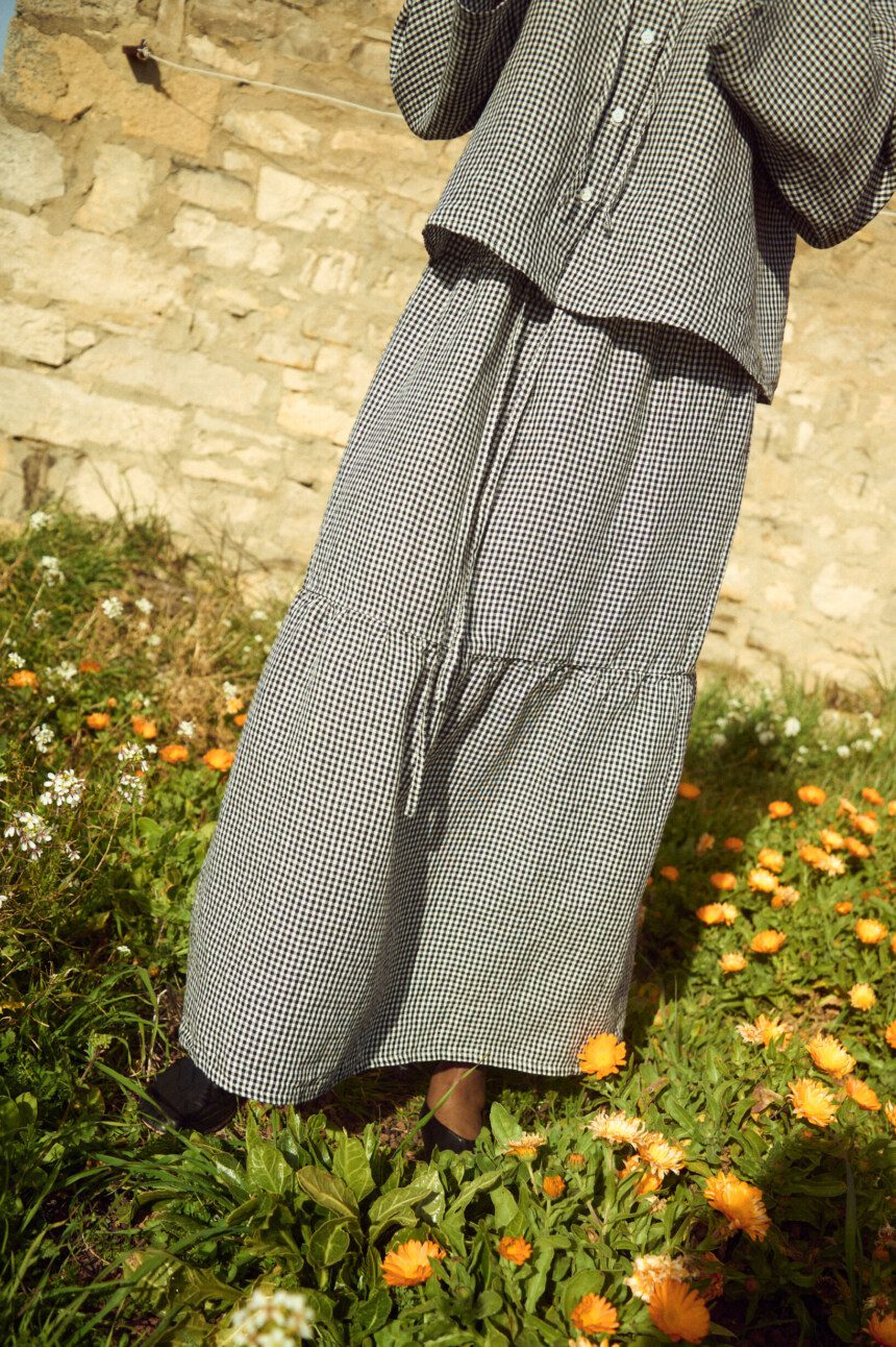 Black gingham linen skirt featuring a gathered lower tier and relaxed, flowing silhouette