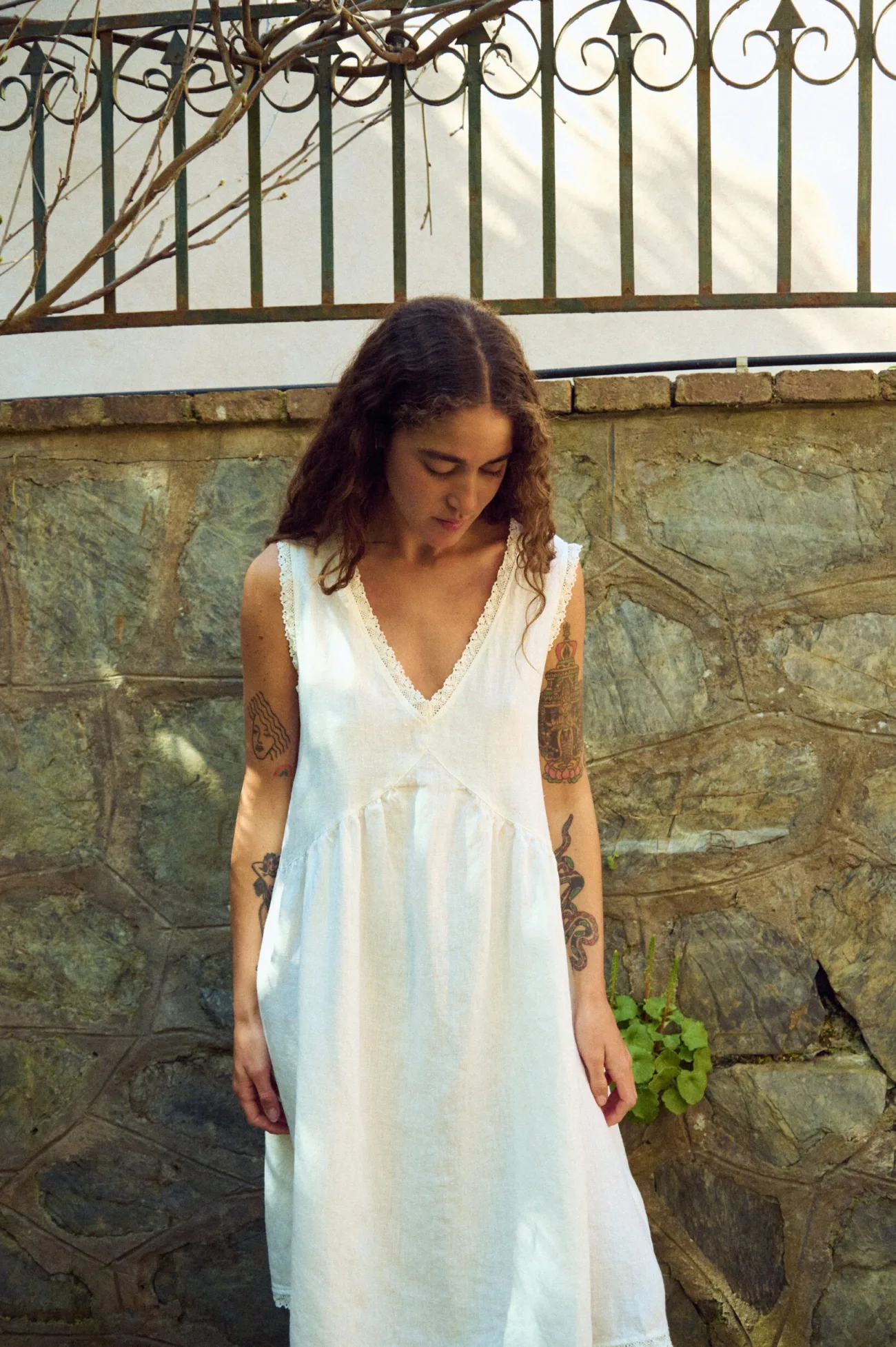 Close front view of milky white linen sleeveless midi dress with V-neck, lace-trim neckline, and softly gathered waist