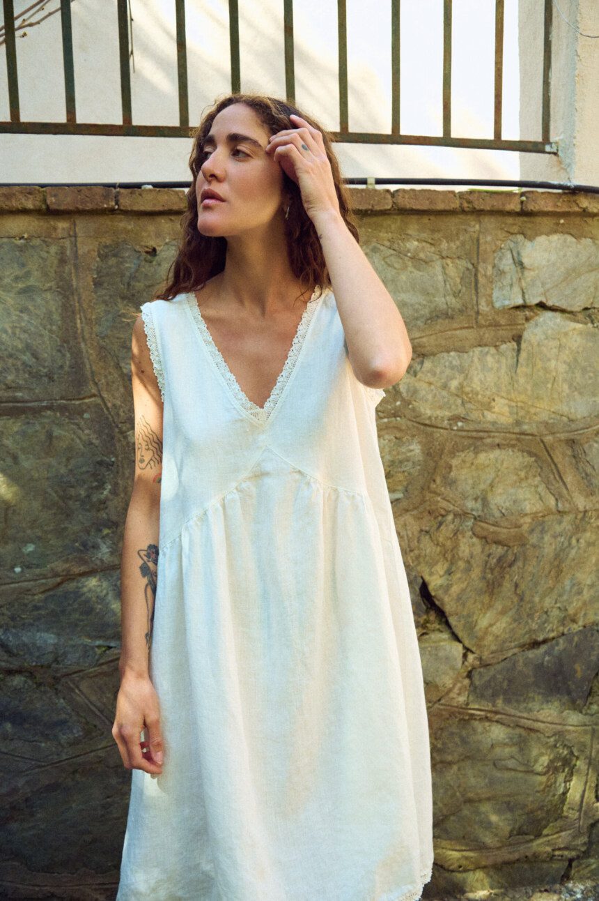 Milky white linen sleeveless midi dress with lace-trim V-neck, gathered bodice, and airy drape