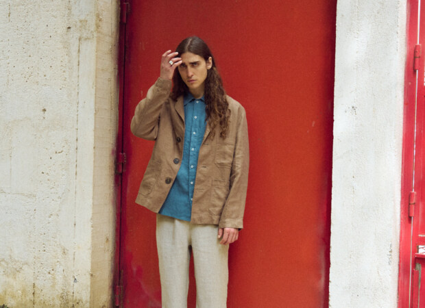 Men’s brown heavy linen jacket with an easy, structured silhouette, classic notched lapels, three-button closure and generous patch pockets, styled with a stellar blue linen shirt and relaxed natural grey linen trousers