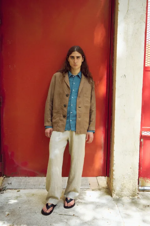 Men’s brown heavy linen jacket with a relaxed blazer-inspired fit, notched lapels, three-button front and roomy patch pockets, layered over a stellar blue linen shirt and loose natural grey linen trousers