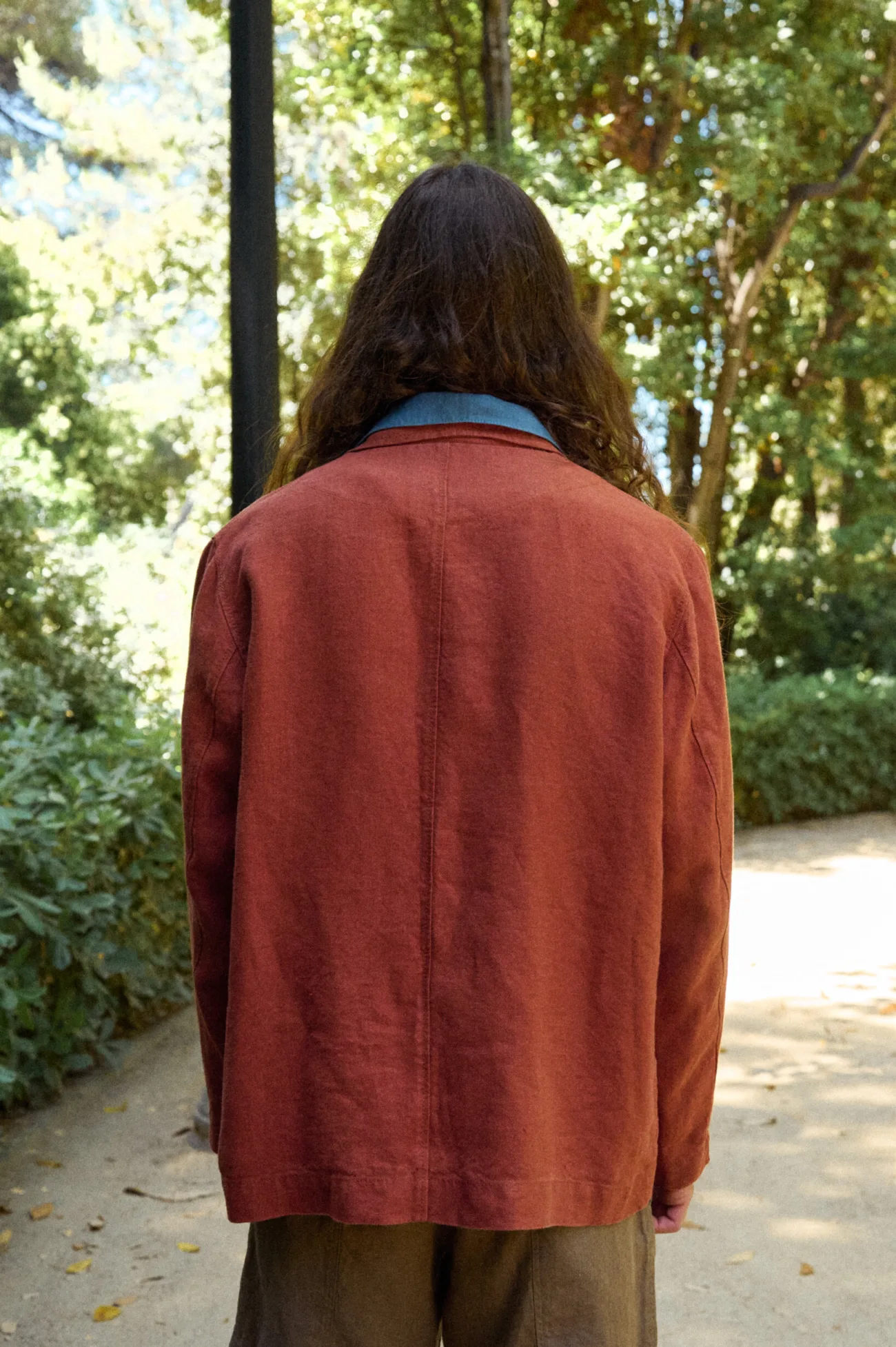 Back view of the men’s terracotta heavy linen jacket, highlighting its clean relaxed cut, straight hem and simple center back seam