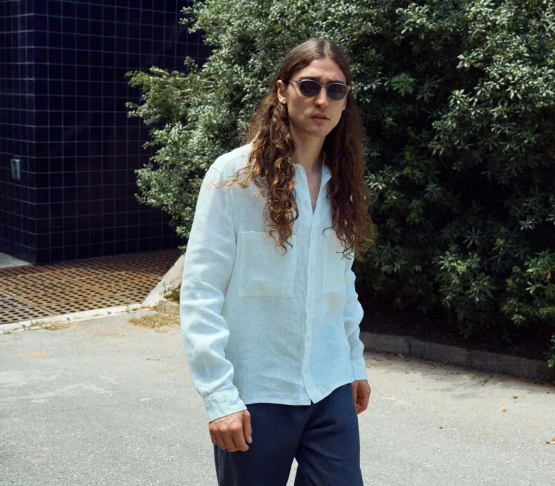 Men’s graphite grey linen trousers cut in an easy, loose silhouette, paired with a milky white linen shirt