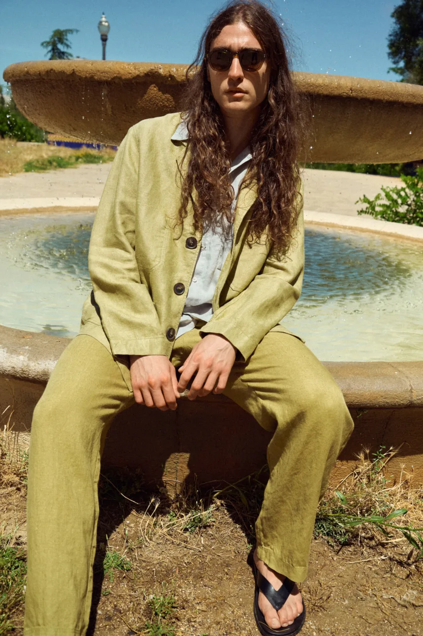Men’s olive heavy linen jacket with a relaxed blazer-inspired silhouette, notched lapels, three-button front and roomy patch pockets, styled with matching olive linen trousers and a light grey linen shirt underneath