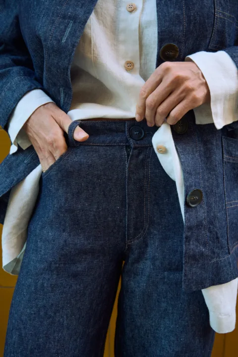 Detail view of blue denim linen jeans with button closure, belt loops, front pocket, and contrast stitching