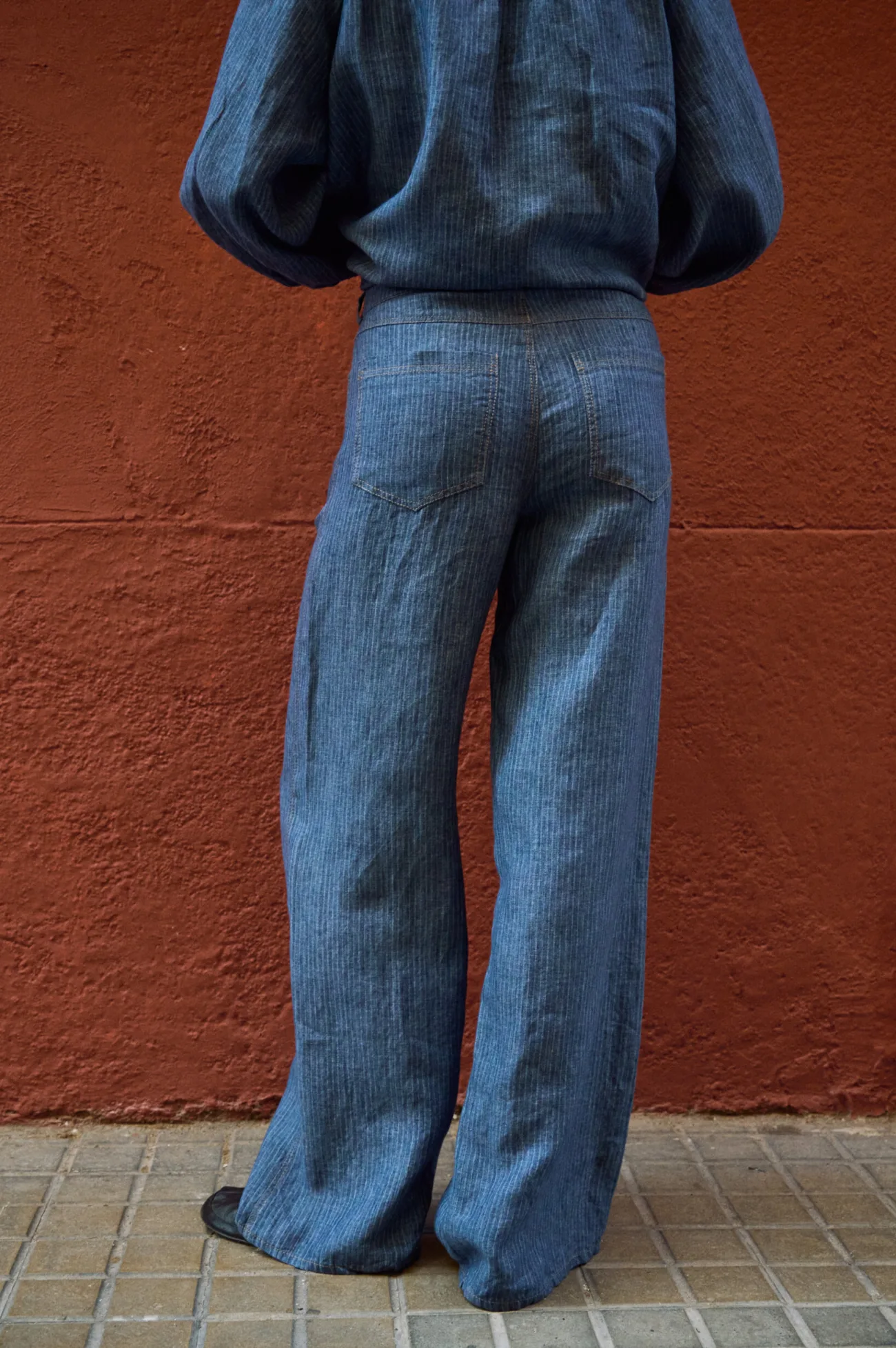 Rear view of blue striped linen wide-leg pants with patch pockets and contrast stitching