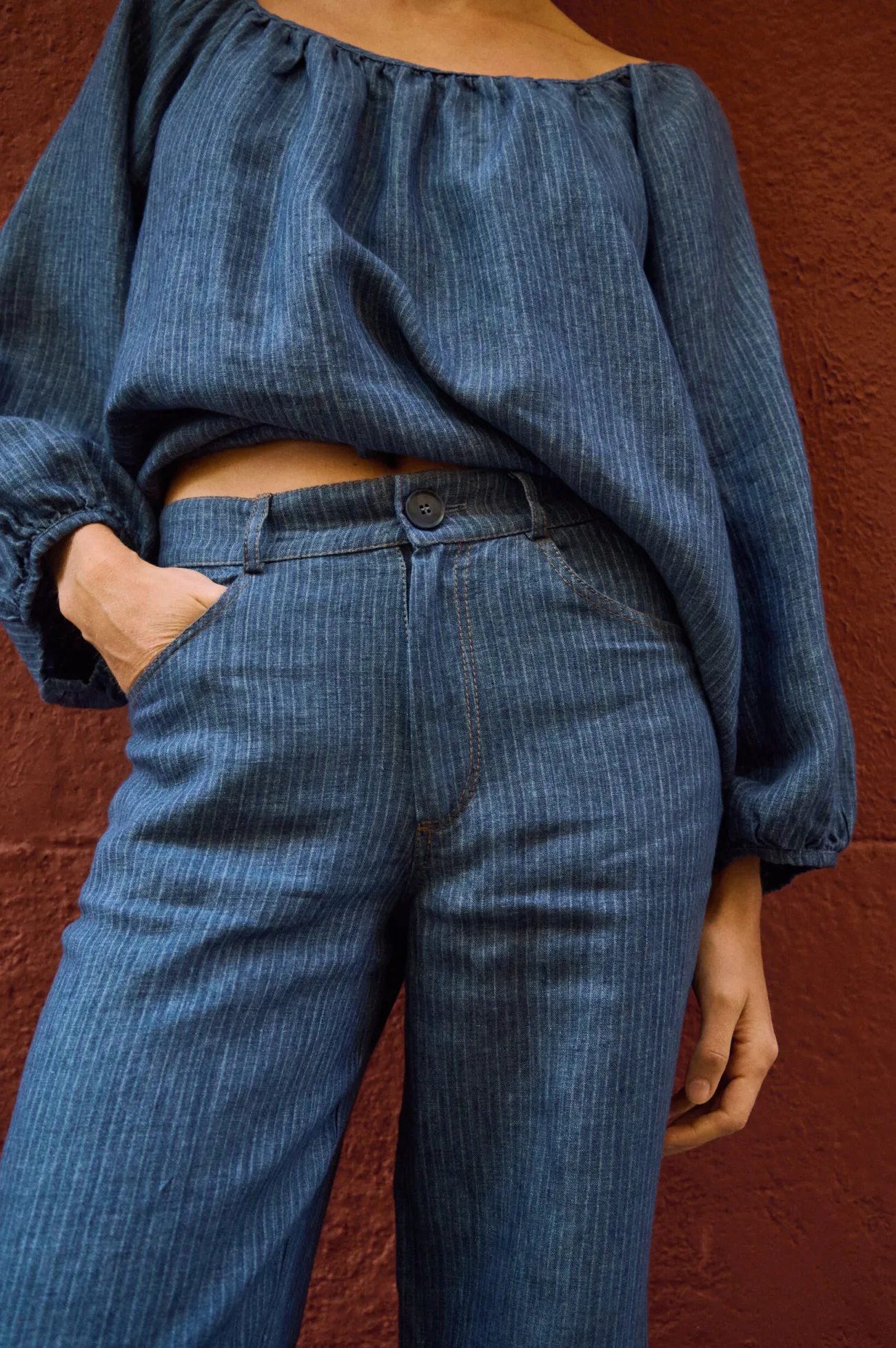 Close-up of blue striped linen pants with a button waist, belt loops, side pockets and contrast stitching