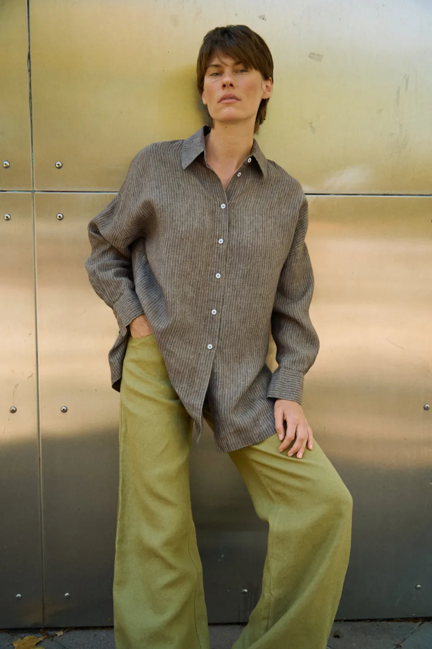 Brown striped linen button-up shirt with a loose draped fit, styled with olive green wide-leg trousers