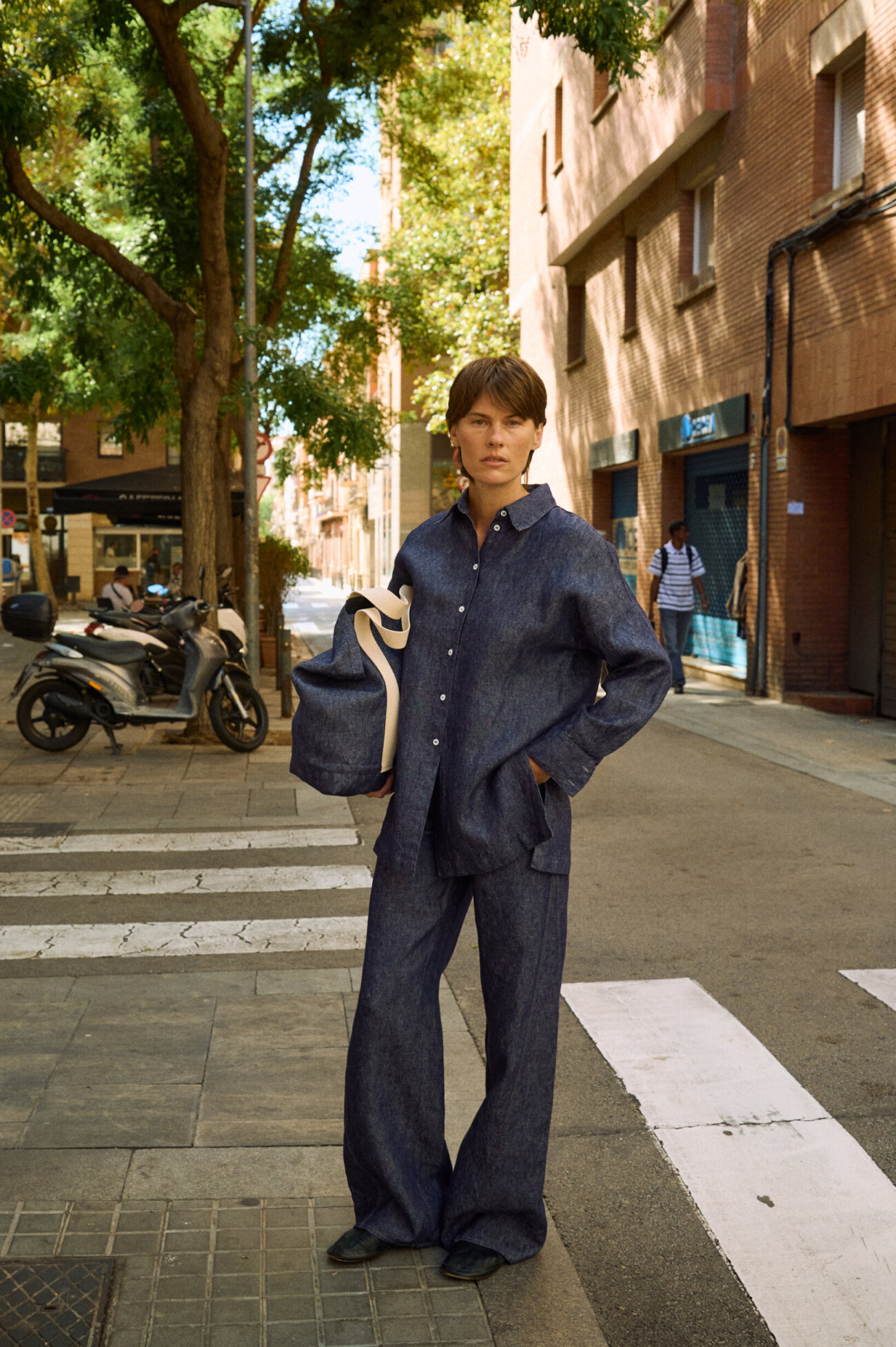 Blue denim linen pants with wide legs, styled with a matching button-down linen shirt and tote bag outdoors