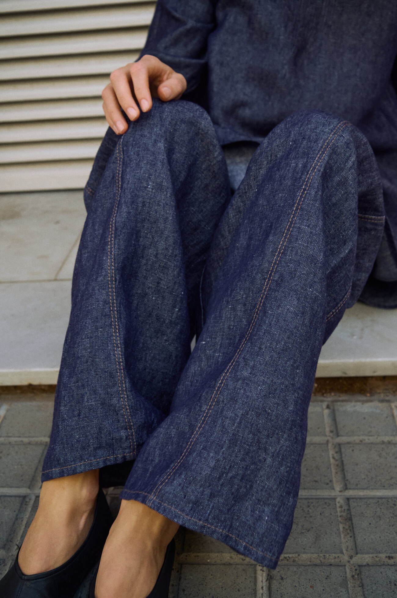 Detail view of blue denim linen pants with wide legs and contrast stitching along the front seams