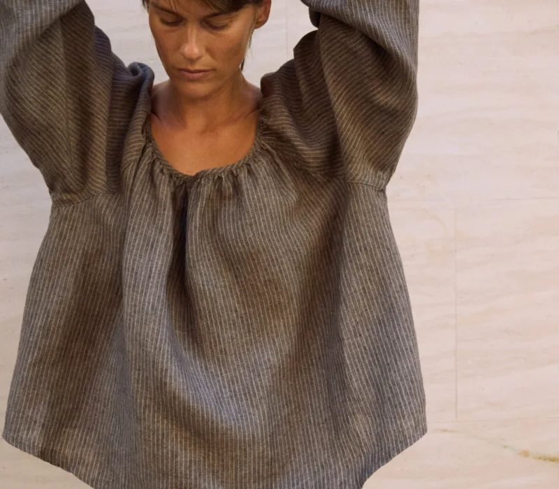 Close-up of a brown striped linen blouse with a softly gathered neckline and loose voluminous sleeves