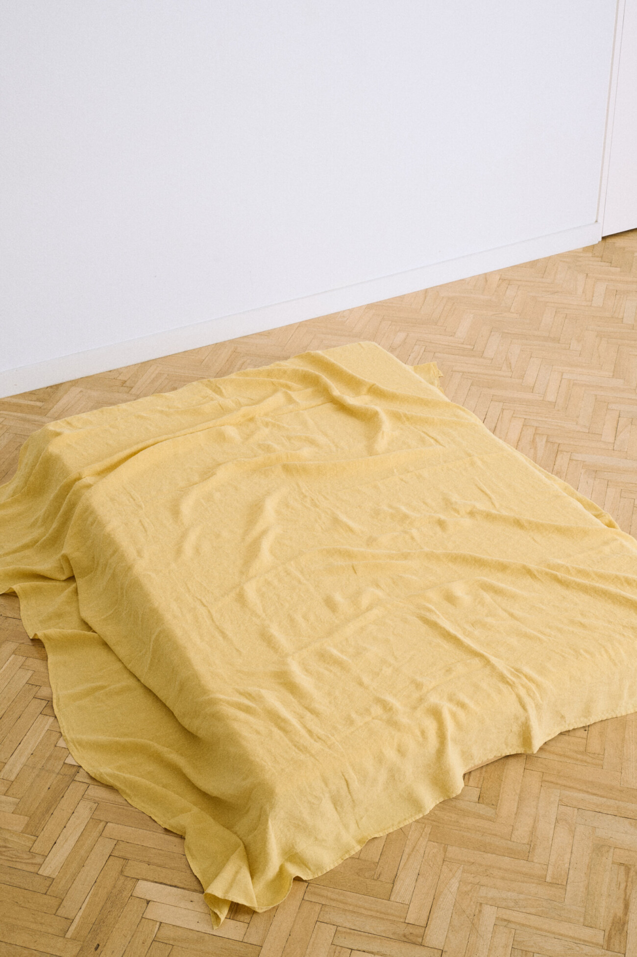 Butter yellow flat linen sheet styled as a bed throw