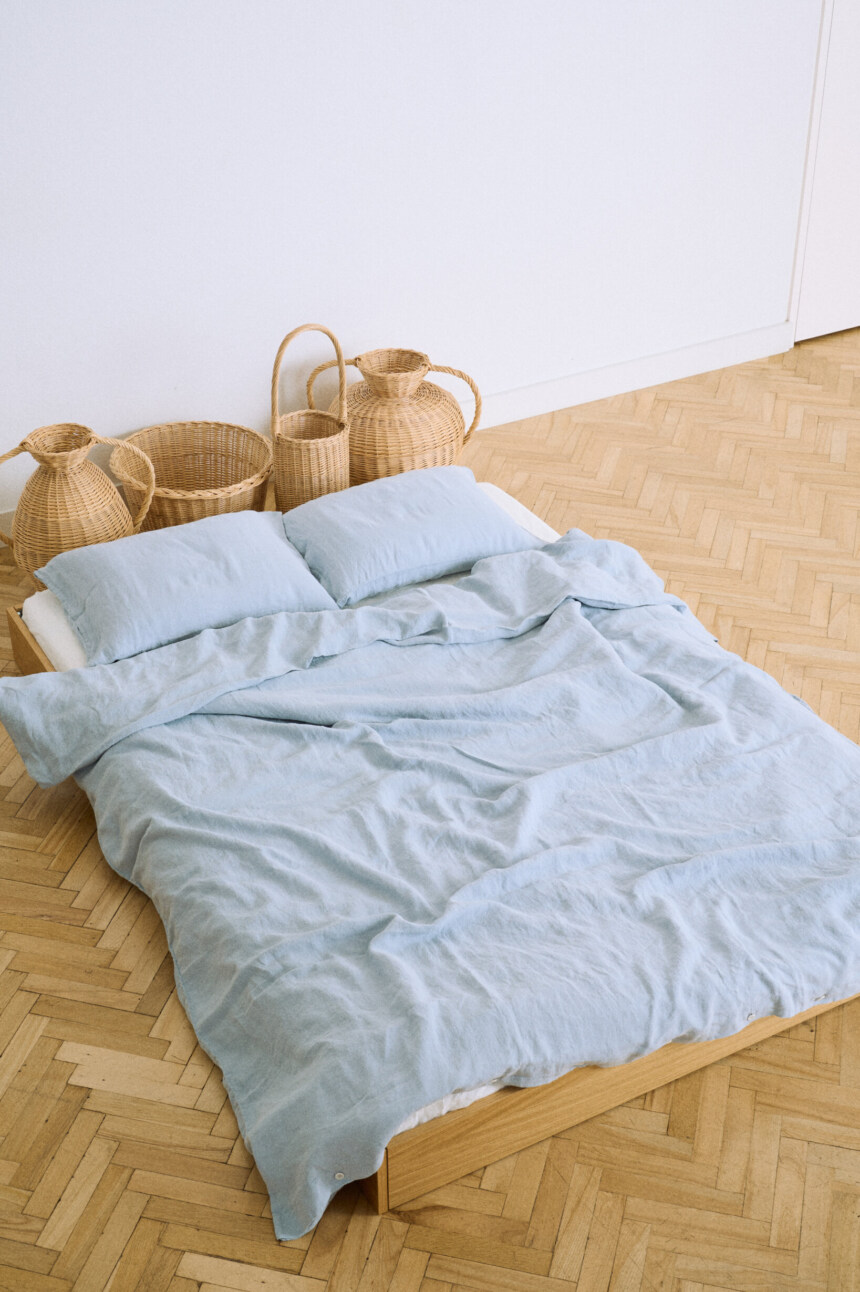 Blue linen duvet cover with matching pillows on a low wooden bed