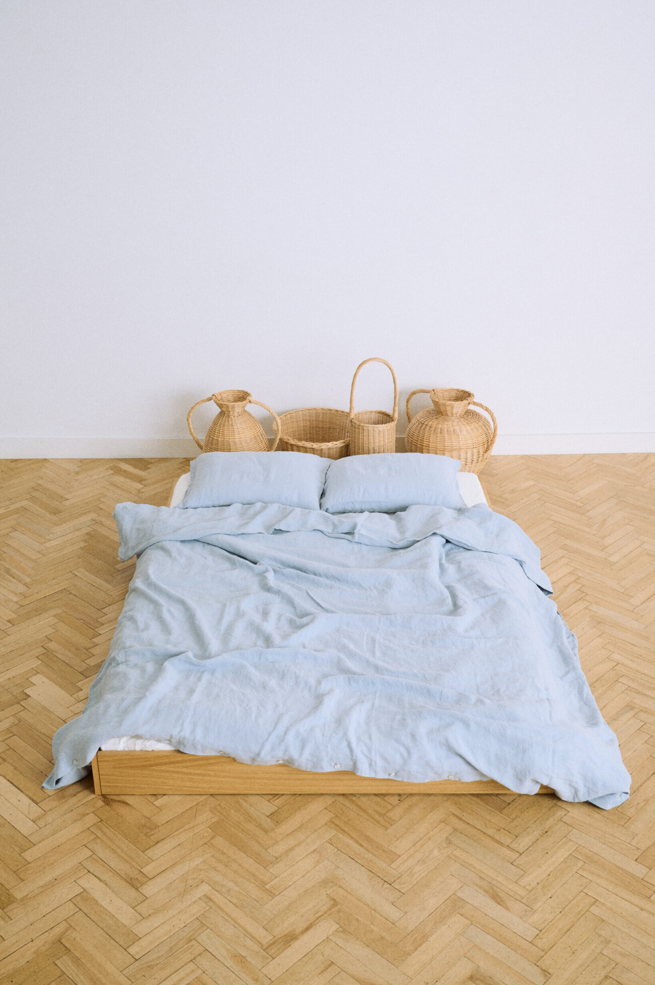 Dusty blue linen duvet cover draped naturally across a wooden platform bed