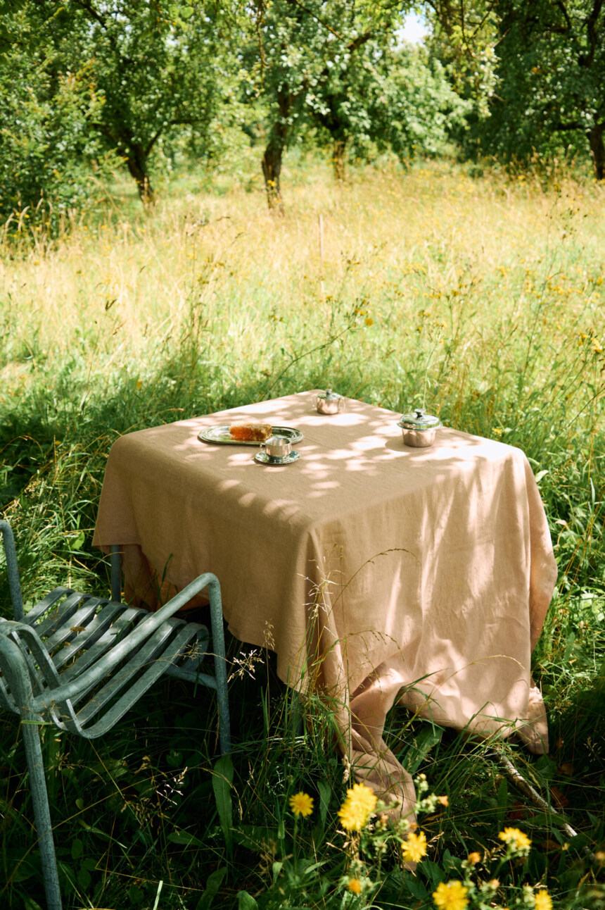 Dusty peach linen tablecloth draped over a dining table.