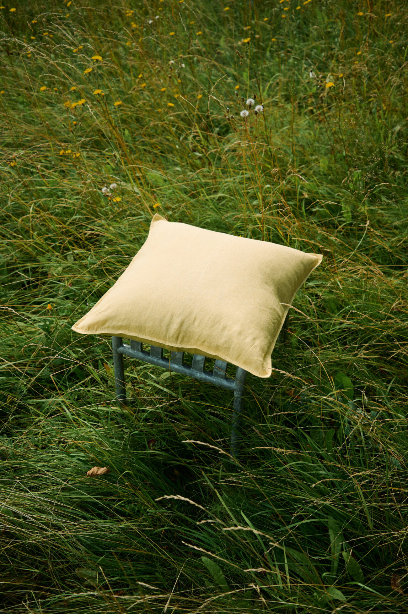 Butter yellow linen pillow cover with decorative stitched edges.