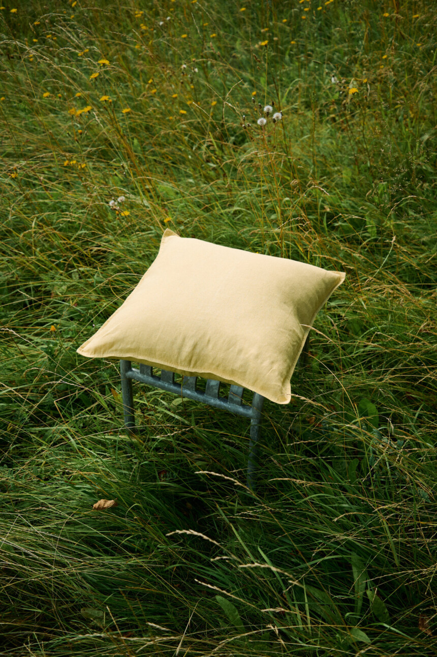 Butter yellow linen pillow cover with decorative stitched edges.