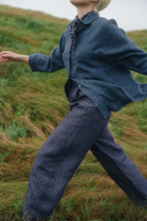 Relaxed blue pinstripe linen shirt with wide three-quarter sleeves, styled with dark blue denim linen trousers and a navy checked scarf