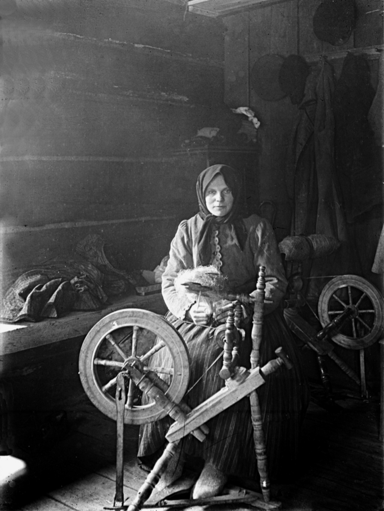 Lithuanian woman spinning flax fibre into yarn using a traditional spinning wheel